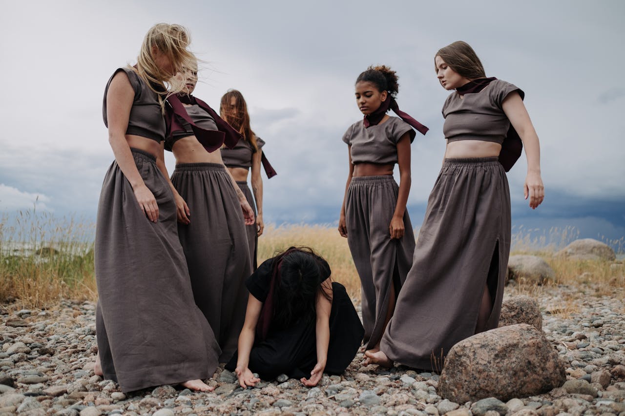 about-04 A group of diverse women standing and kneeling on a rocky field, conveying unity.