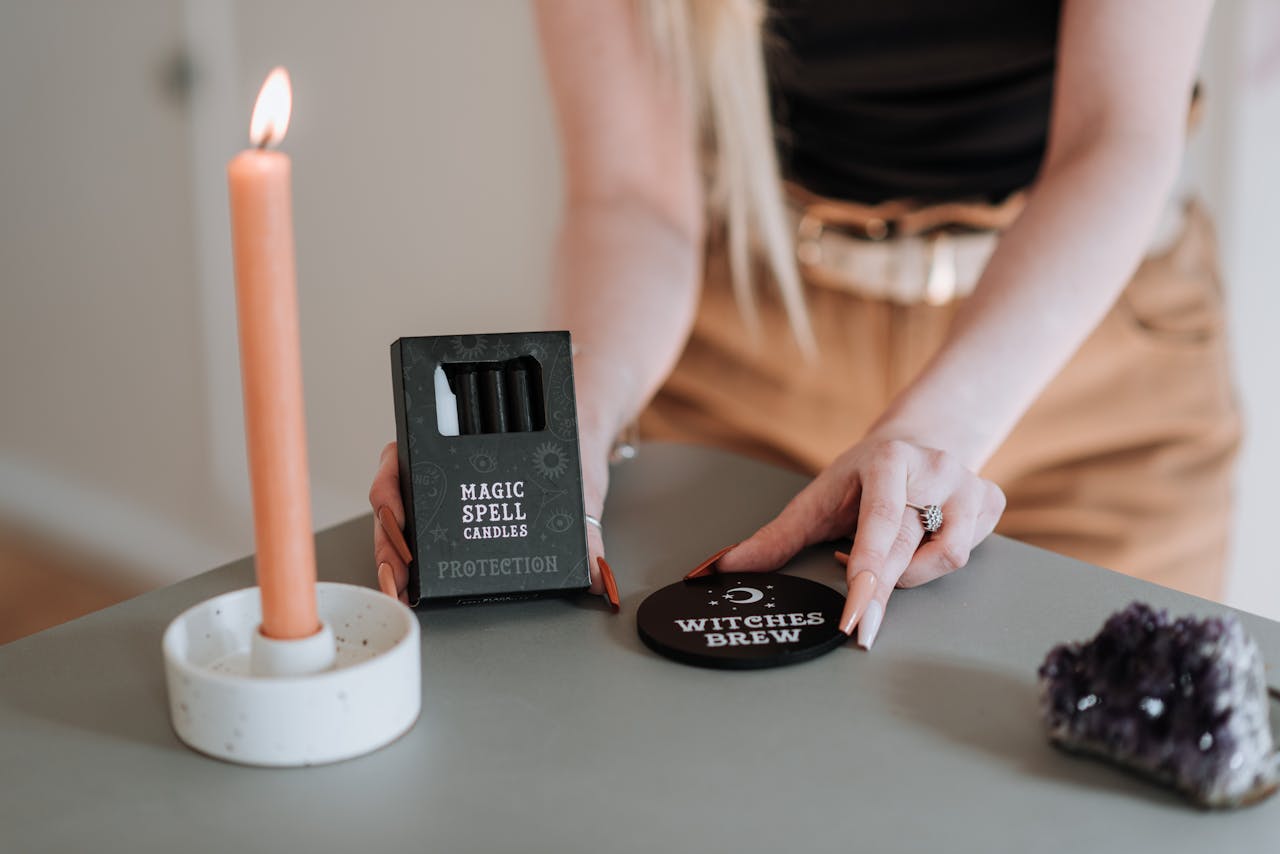 menu-01 A mystical witchcraft ritual setup featuring a burning candle, magic spell candles, and an amethyst crystal.